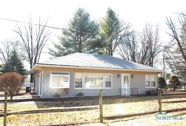 view of front of property featuring fence, a front lawn, and roof with shingles