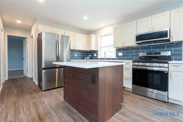 kitchen with a kitchen island, decorative backsplash, stainless steel appliances, and wood finished floors