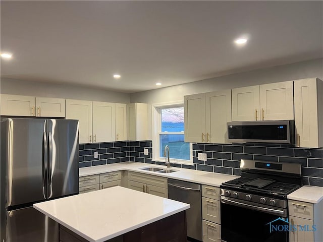 kitchen with appliances with stainless steel finishes, light countertops, a sink, and decorative backsplash