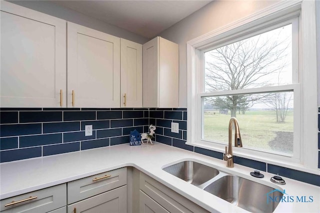 kitchen featuring plenty of natural light, tasteful backsplash, light countertops, and a sink