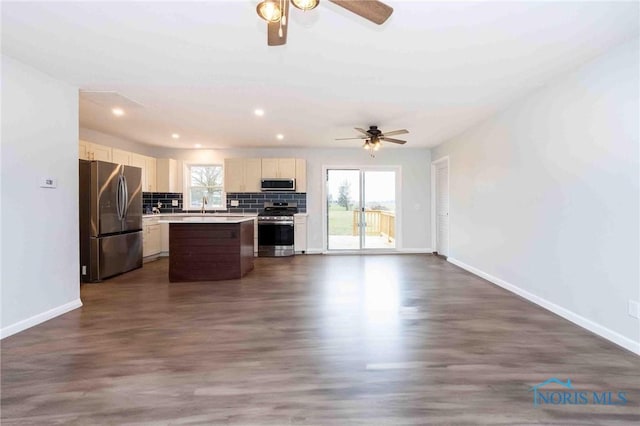 kitchen featuring open floor plan, appliances with stainless steel finishes, backsplash, and a healthy amount of sunlight