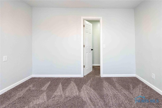 carpeted empty room featuring baseboards