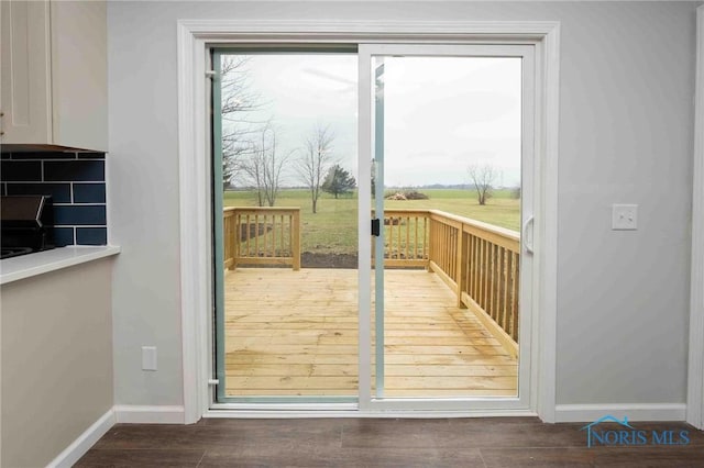 doorway to outside featuring baseboards and wood finished floors