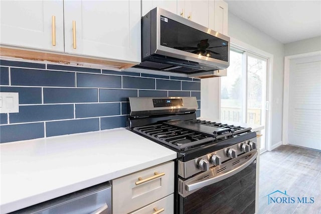 kitchen featuring tasteful backsplash, white cabinets, light wood-style flooring, stainless steel appliances, and light countertops