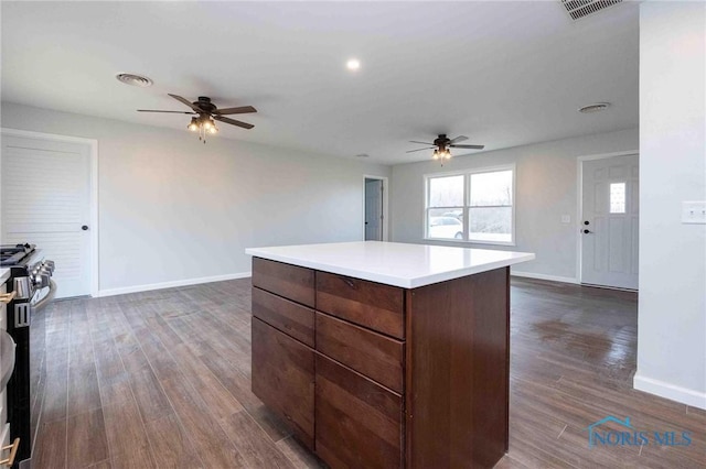 kitchen with a center island, light countertops, dark wood finished floors, and baseboards