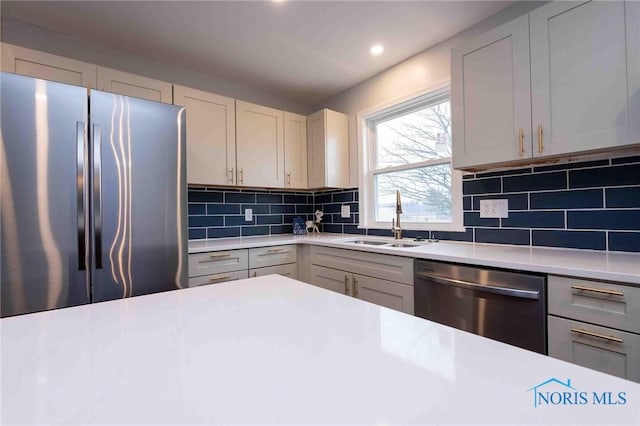 kitchen with decorative backsplash, appliances with stainless steel finishes, light countertops, a sink, and recessed lighting