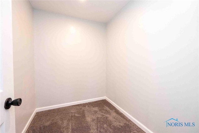 empty room with dark colored carpet and baseboards