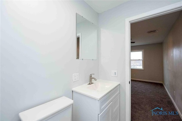 bathroom featuring visible vents, baseboards, vanity, and toilet