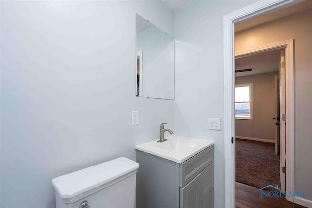 half bath with vanity, toilet, and baseboards