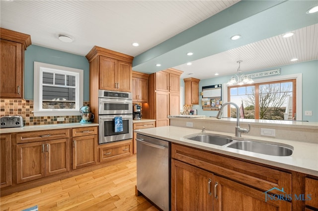 kitchen featuring appliances with stainless steel finishes, brown cabinetry, a sink, and light countertops