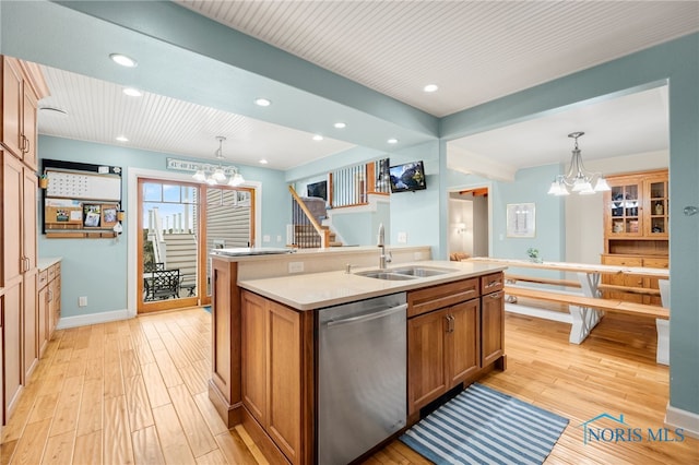 kitchen with dishwasher, an island with sink, light wood-type flooring, a chandelier, and a sink