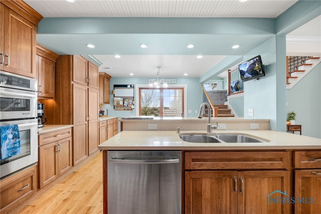 kitchen featuring appliances with stainless steel finishes, light countertops, brown cabinets, and a sink