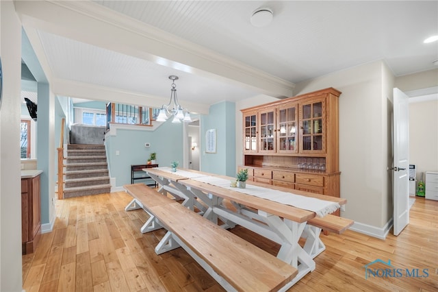 dining space with light wood finished floors, baseboards, and stairway