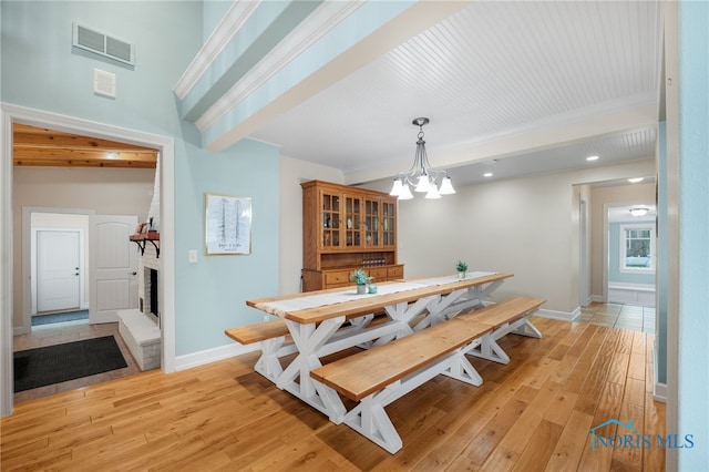 dining room with light wood finished floors, a brick fireplace, visible vents, and baseboards