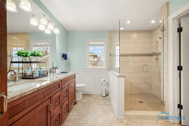 full bath featuring a stall shower, a wainscoted wall, and a sink