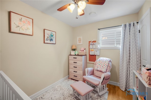 sitting room featuring a ceiling fan, baseboards, and wood finished floors