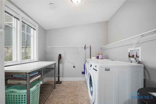 clothes washing area with light tile patterned floors, laundry area, washing machine and dryer, and baseboards