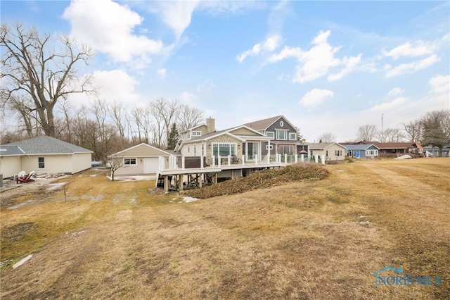 back of house featuring a chimney, a residential view, a deck, and a lawn