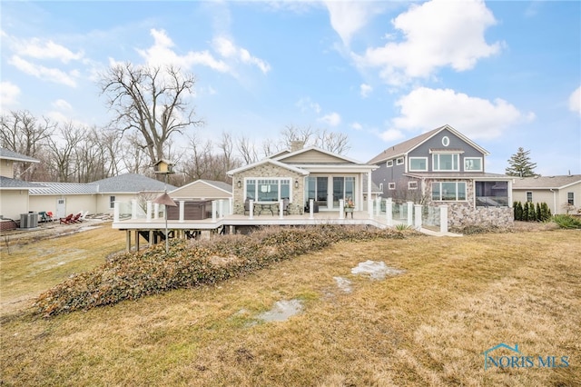 view of front facade featuring central air condition unit, stone siding, a deck, and a front yard