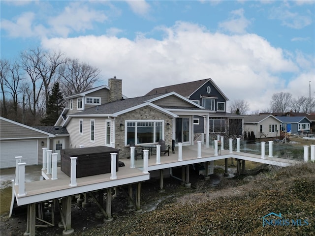 back of house featuring stone siding, a chimney, and a wooden deck