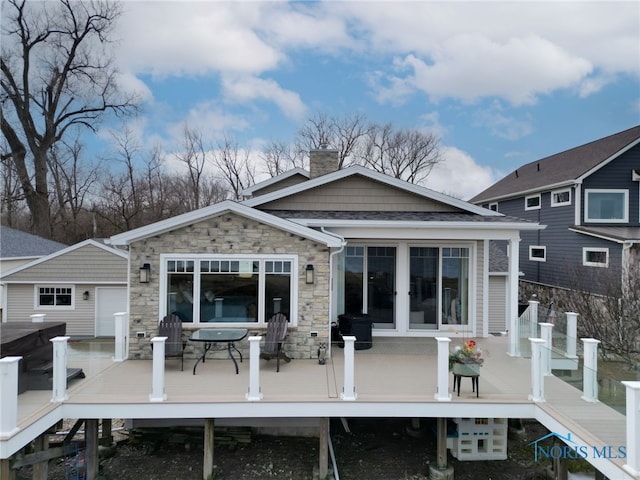 back of property with stone siding, a chimney, and a wooden deck