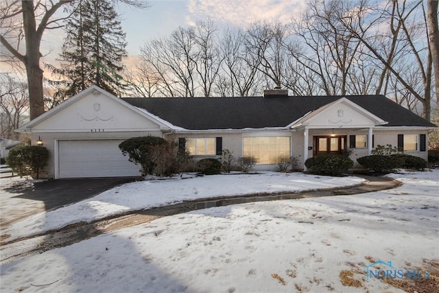 view of front of property featuring a garage, aphalt driveway, a chimney, and brick siding