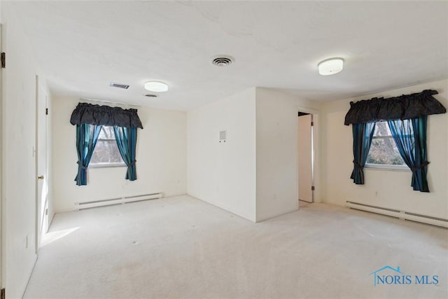 spare room with carpet floors, a baseboard radiator, and visible vents