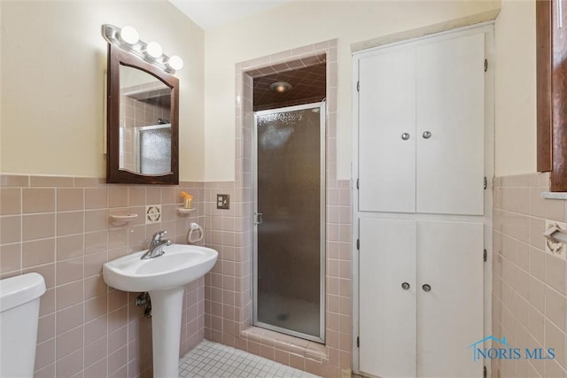 full bathroom featuring a wainscoted wall, toilet, a stall shower, and tile walls