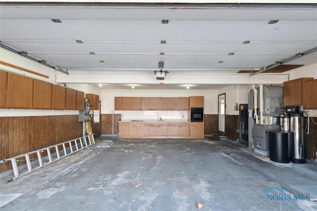 garage with a garage door opener, a wainscoted wall, and wooden walls