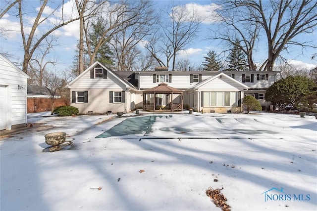 back of house with crawl space, brick siding, a chimney, and a gazebo