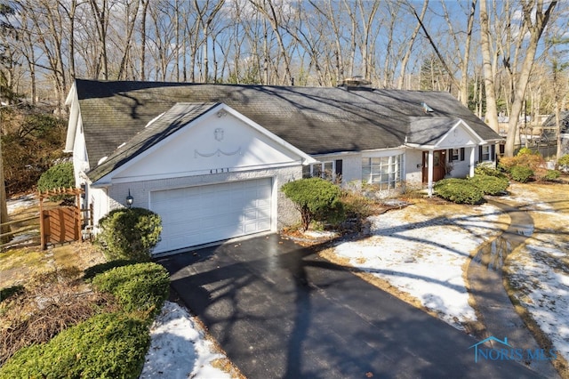 ranch-style house featuring aphalt driveway, a garage, brick siding, a shingled roof, and fence