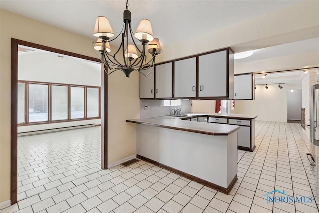 kitchen featuring a baseboard radiator, light tile patterned flooring, a peninsula, hanging light fixtures, and a wealth of natural light