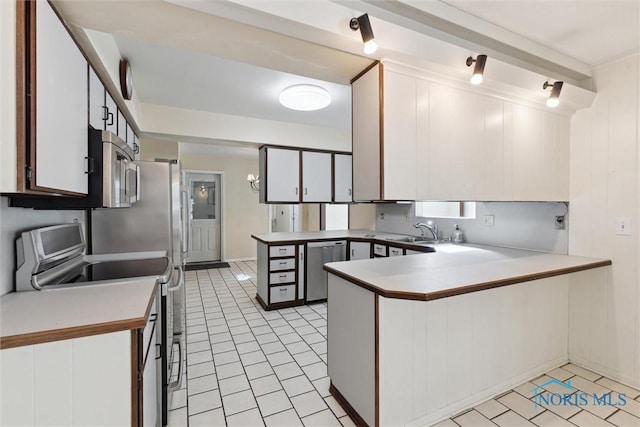 kitchen featuring white cabinets, a peninsula, stainless steel appliances, light countertops, and a sink