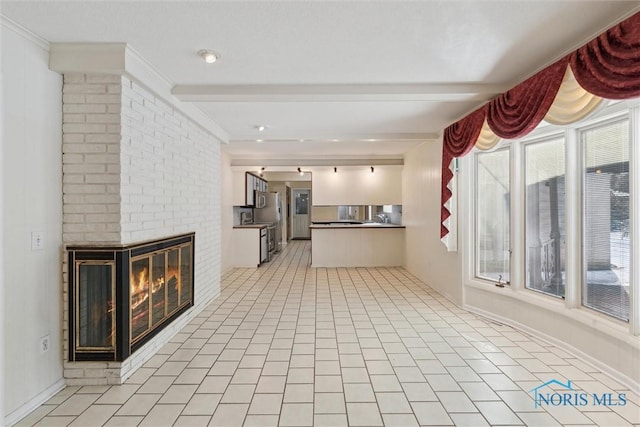 unfurnished living room with a fireplace, beamed ceiling, and light tile patterned floors