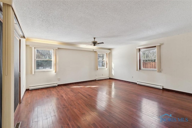 spare room with a baseboard radiator, visible vents, and hardwood / wood-style flooring