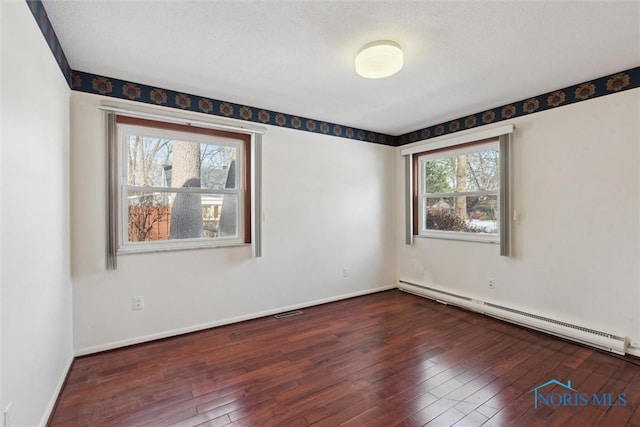 unfurnished room with plenty of natural light, baseboard heating, and dark wood-type flooring