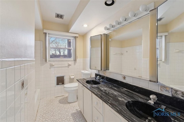 bathroom with tile walls, a sink, visible vents, and tile patterned floors