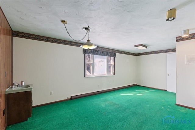 carpeted empty room with baseboards, baseboard heating, and a sink