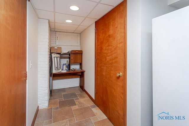 corridor with a paneled ceiling, baseboards, stone finish floor, and recessed lighting