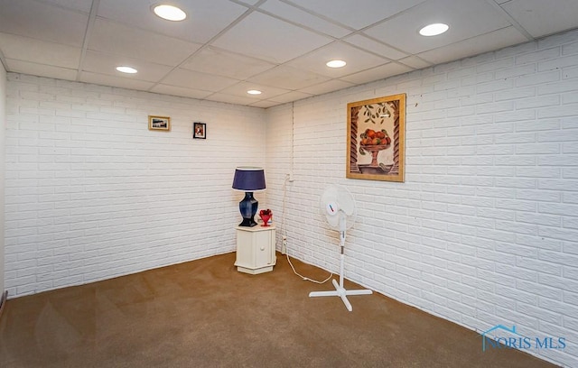 interior space with a paneled ceiling, brick wall, and recessed lighting