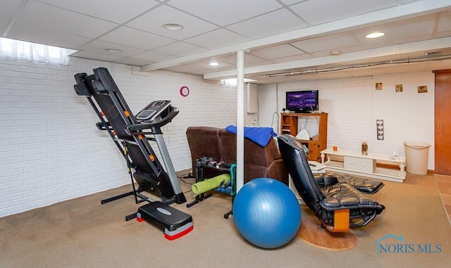 workout room with carpet, brick wall, and a drop ceiling