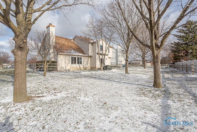 back of house featuring a chimney and fence