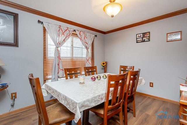 dining area featuring crown molding, baseboards, and wood finished floors