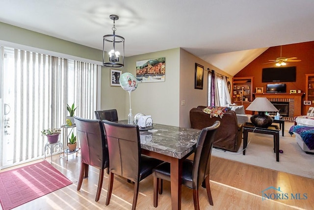 dining room featuring light wood-style flooring, vaulted ceiling, and ceiling fan with notable chandelier