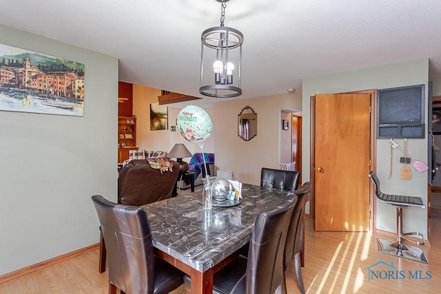 dining area with light wood-style floors, baseboards, and a notable chandelier