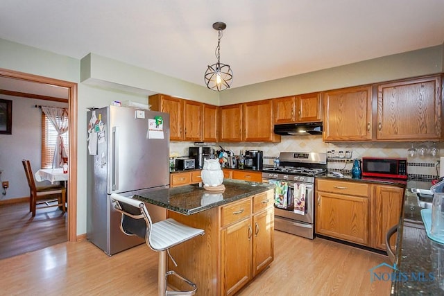 kitchen with stainless steel appliances, light wood-style floors, brown cabinetry, a kitchen island, and under cabinet range hood