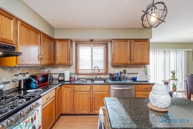 kitchen featuring tasteful backsplash, appliances with stainless steel finishes, a sink, and brown cabinets