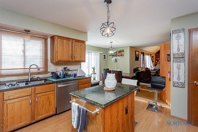 kitchen with brown cabinets, light wood-style flooring, stainless steel dishwasher, a kitchen island, and a sink