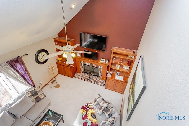 living area with vaulted ceiling, carpet, a ceiling fan, and a brick fireplace