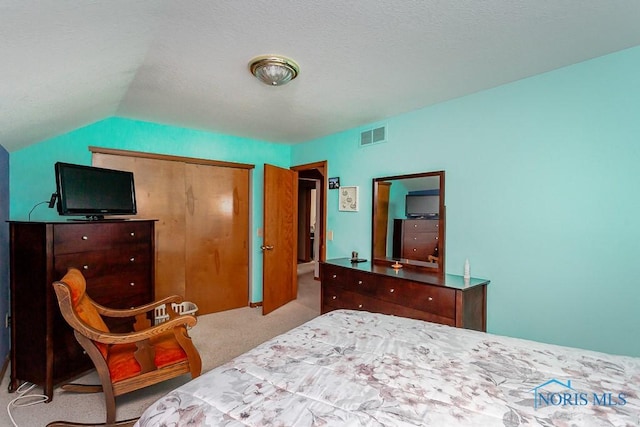 bedroom with carpet, a closet, visible vents, and lofted ceiling